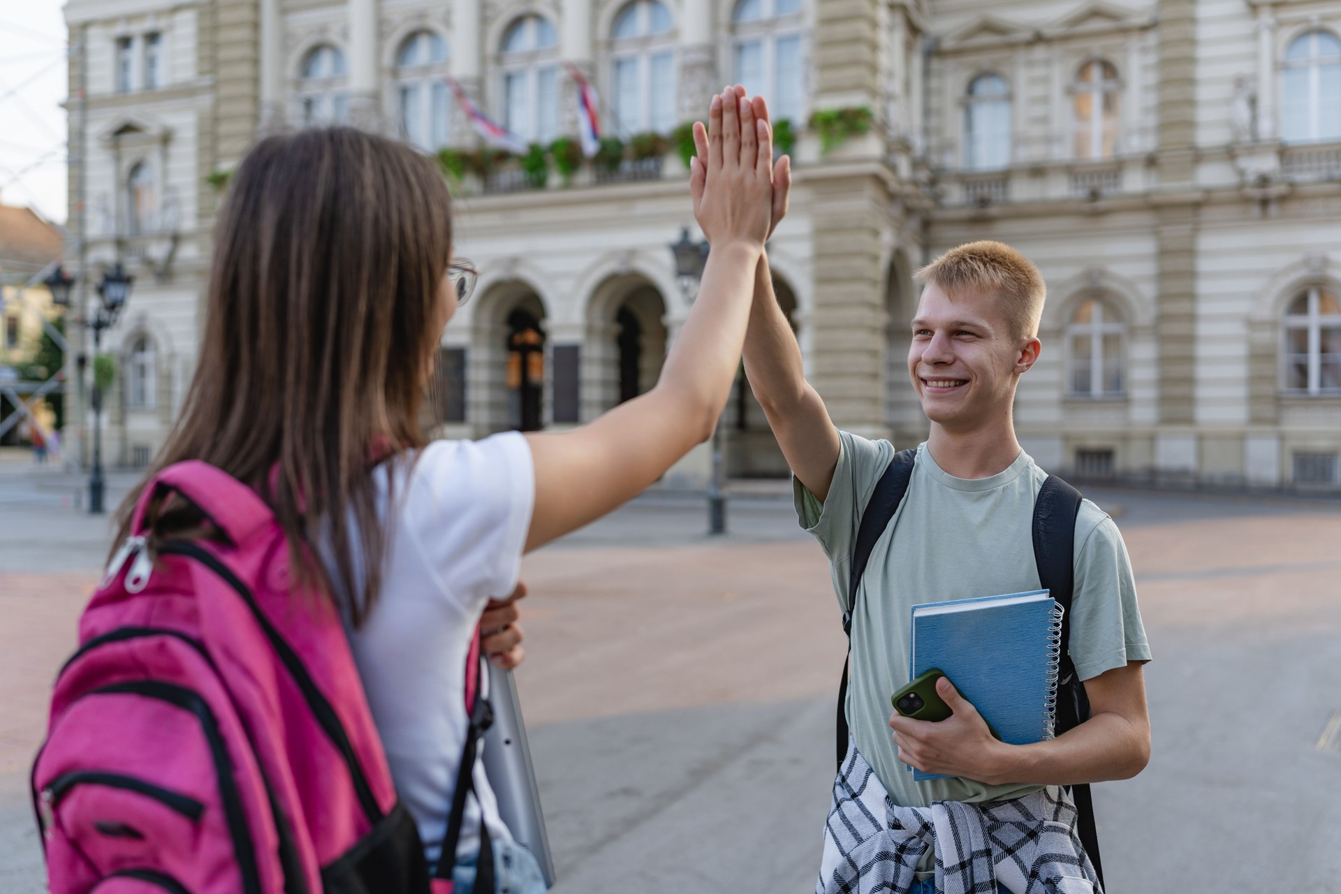 Students giving high-fives in front of historic edifice.